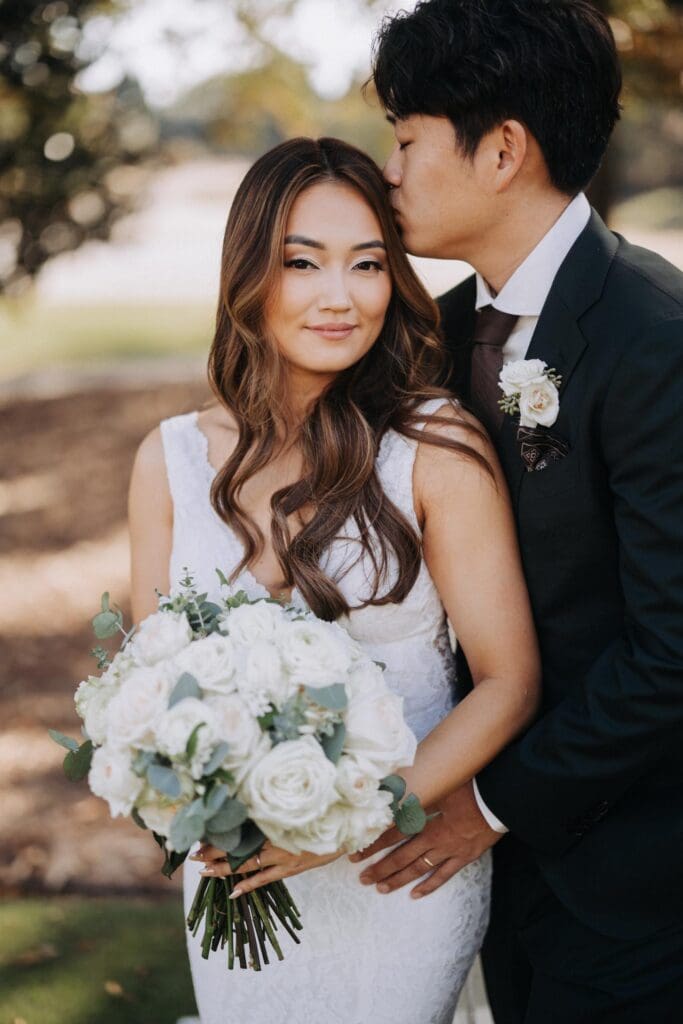 Bride and groom portrait at TPC Sugarloaf featuring romantic ivory garden rose bridal bouquet