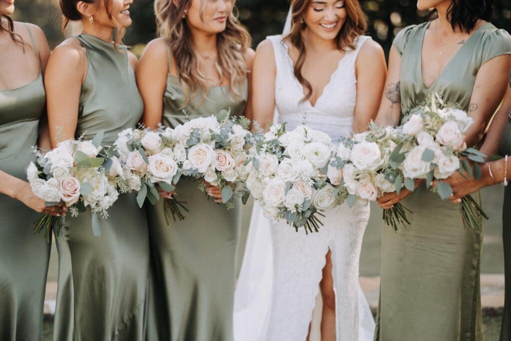 ride with bridesmaids in sage green dresses holding blush and ivory garden rose bouquets