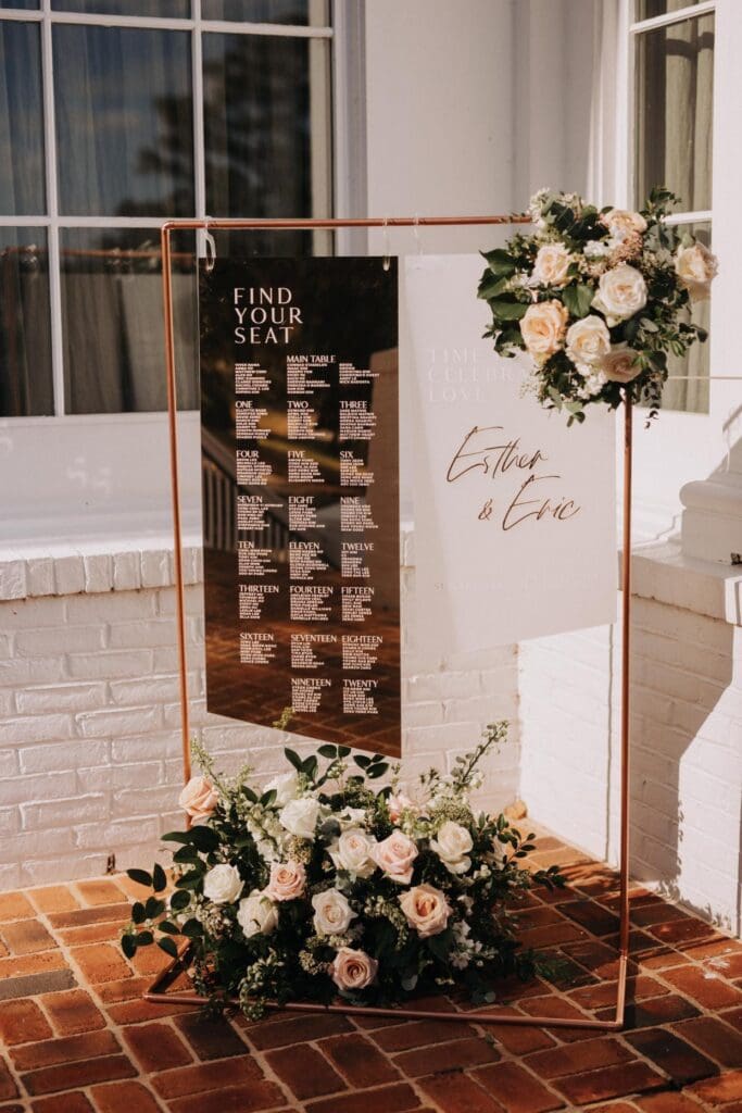 Elegant wedding seating chart display with blush roses and greenery at TPC Sugarloaf reception