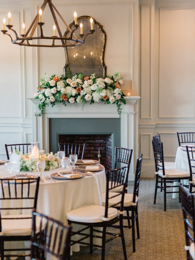 Elegant fireplace floral installation featuring hydrangeas, roses, and greenery at a Sugarloaf Country Club wedding reception.