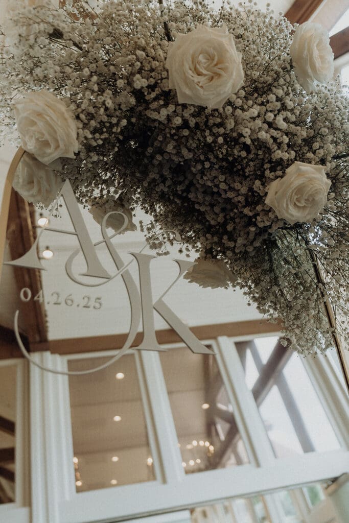 Welcome sign with floral swag in white roses and baby's breath at Country Club of the South