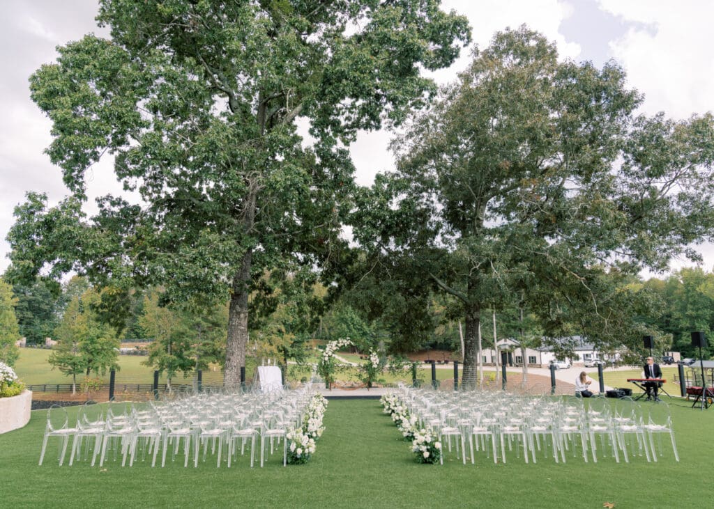 High-end outdoor wedding ceremony design at The Revere with layered white florals, petal-lined aisle, and garden arch backdrop