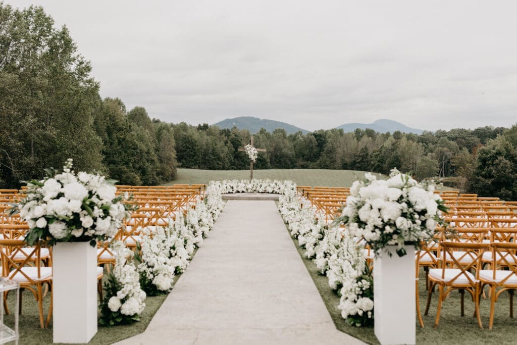 Wide view of floral lined ceremony aisle with all white garden style flowers North Georgia venue