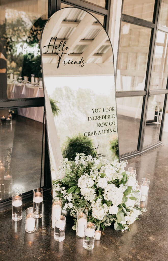 Wedding welcome sign with lush white garden style floral arrangement
