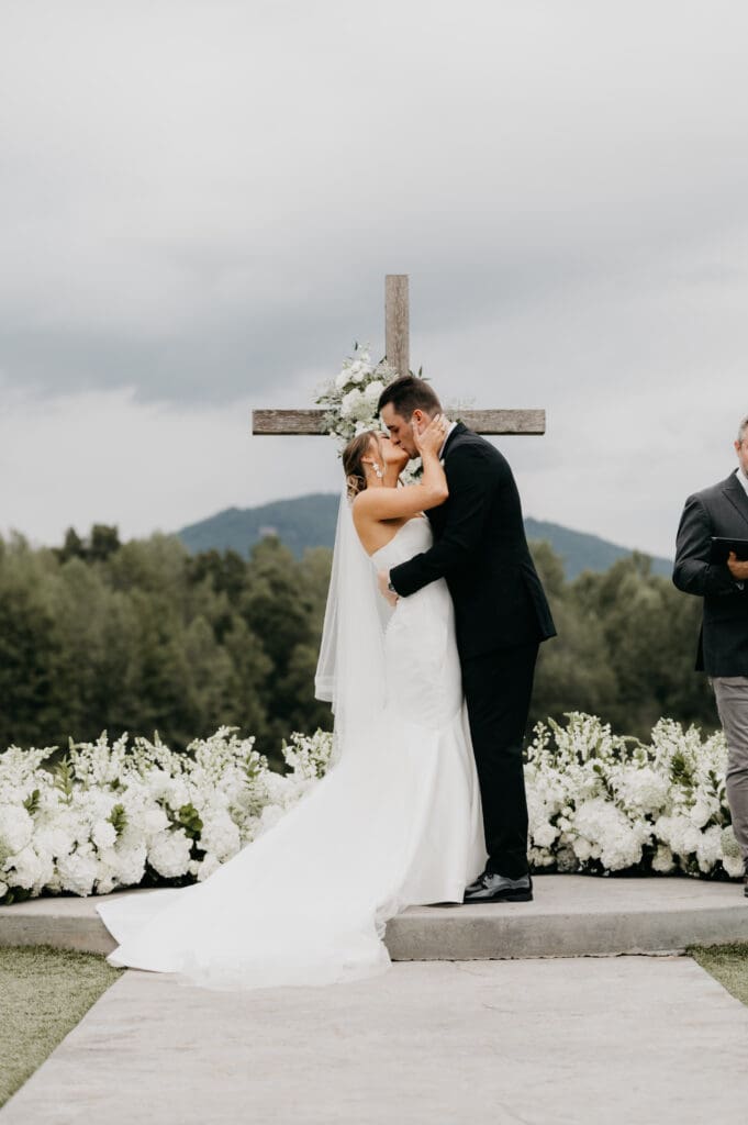 Outdoor wedding ceremony at Meadows at Mossy Creek with white aisle flowers, mountain backdrop, and floral cross by a North Georgia luxury wedding florist