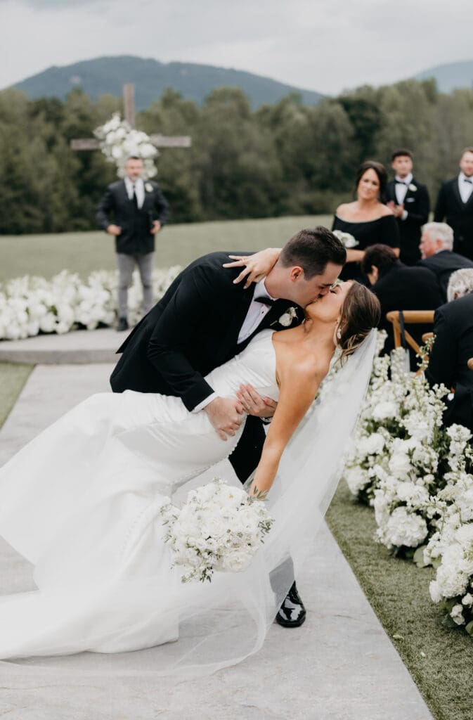 Bride and groom embracing outdoors at Meadows at Mossy Creek with classic all white bridal bouquet by a North Georgia luxury wedding florist