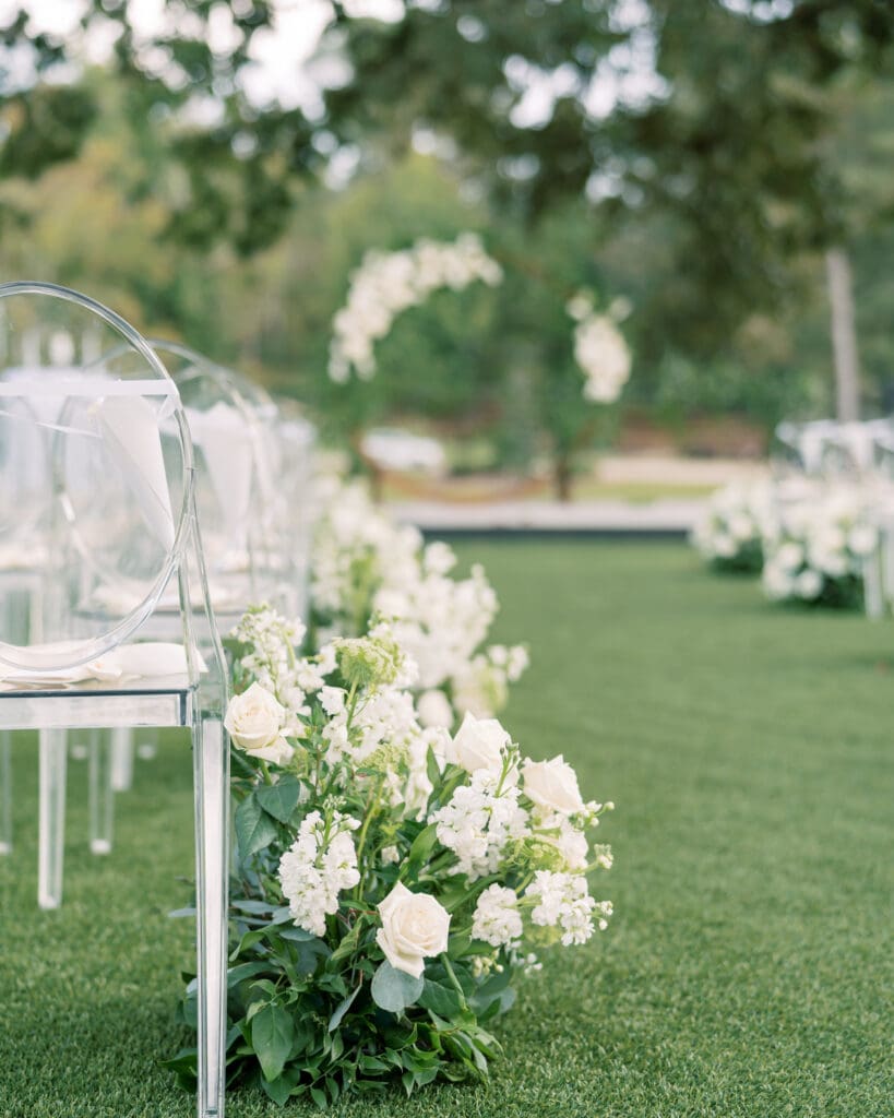 Atlanta luxury wedding at The Revere with clear ghost chairs, white garden floral aisle design, and custom ceremony arch