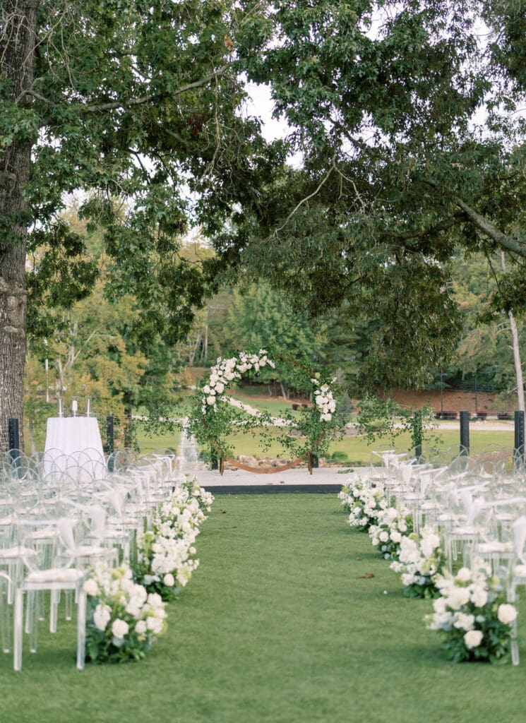 Luxury outdoor wedding ceremony at The Revere in Atlanta with custom white floral aisle arrangements and garden-inspired ceremony arch