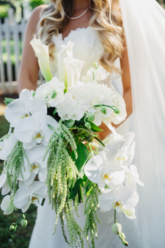 “Bride holding cascading orchid bouquet during Greenfield Farms wedding ceremony”