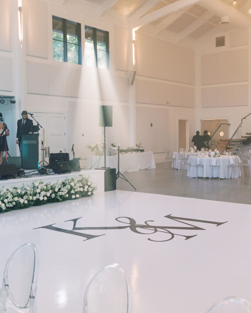 Luxury wedding reception at The Revere in Atlanta featuring white dance floor monogram and low white floral stage installation