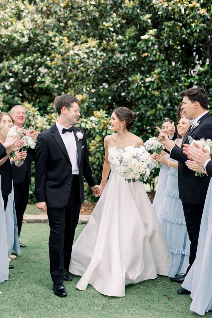 Bride and groom walking past lush florals at TPC Sugarloaf Wedding 