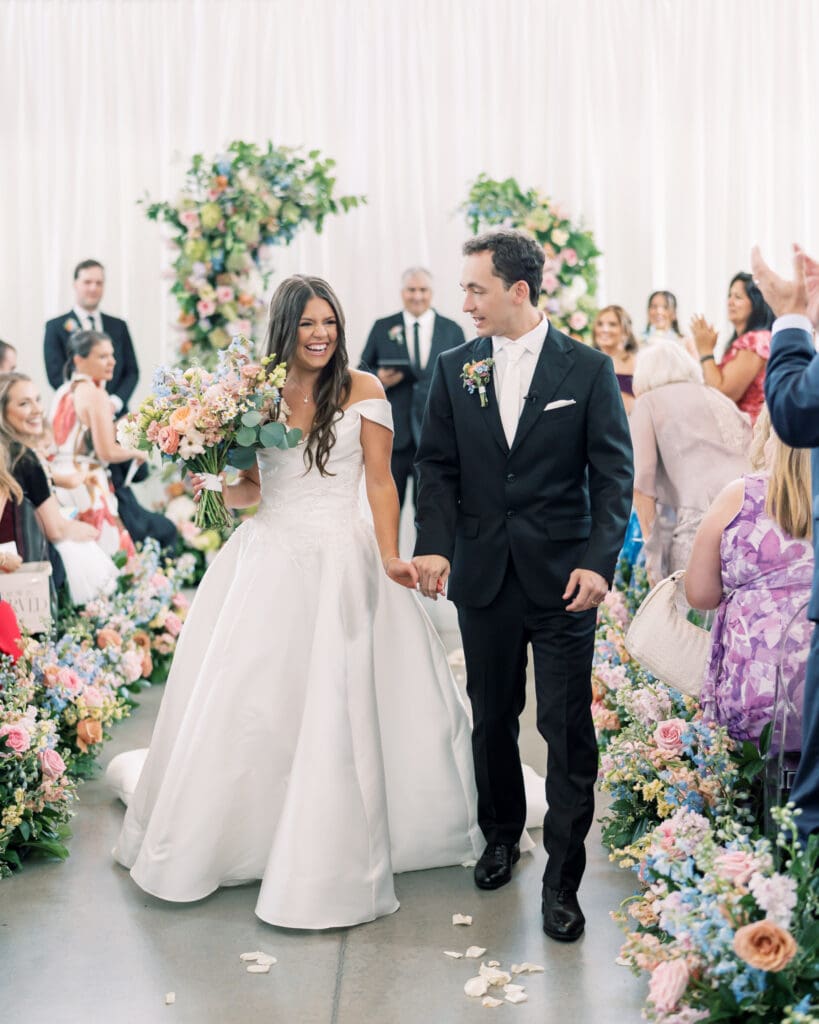 Bride and groom ceremony exit through colorful aisle meadows at The Revere Wedding Venue