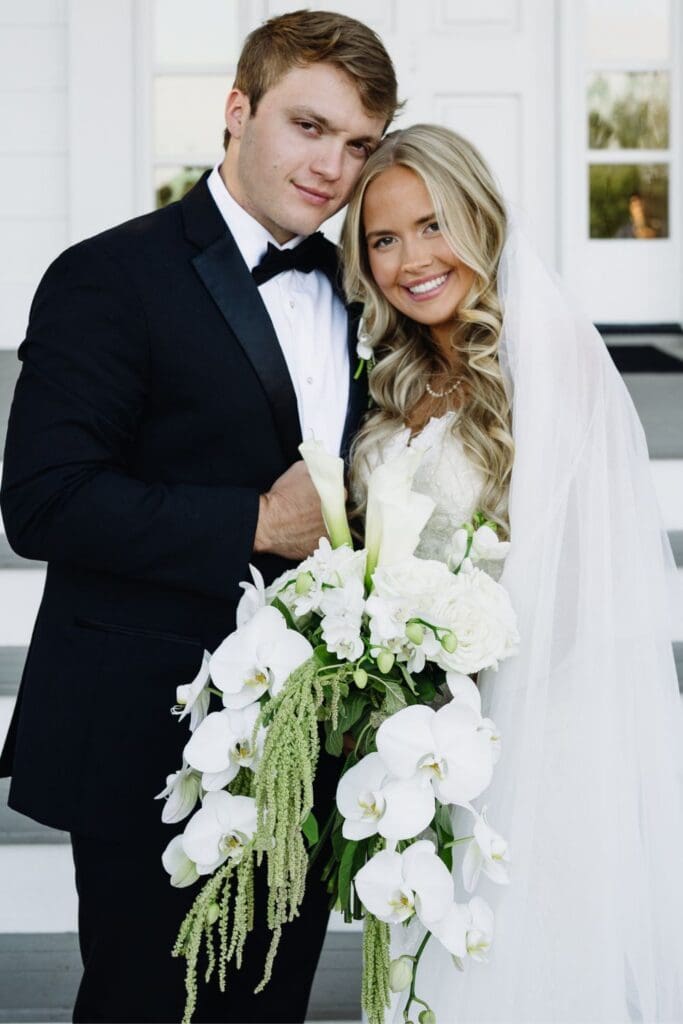 Newlyweds posing with luxury white wedding flowers outside Greenfield Farm in North Georgia.