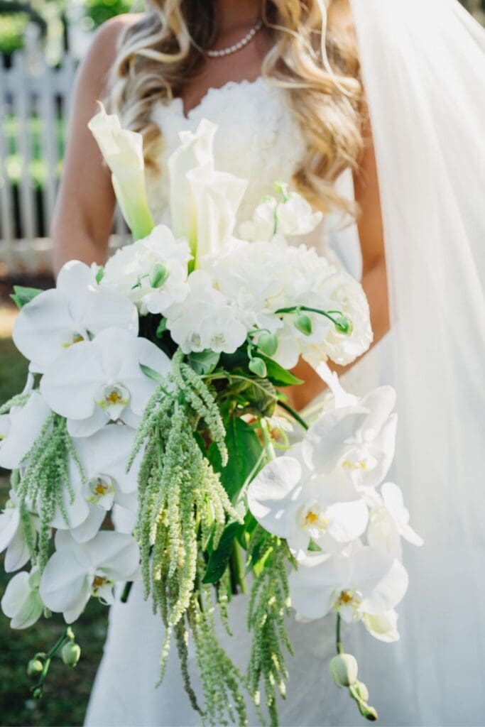 Cascading bridal bouquet featuring white phalaenopsis orchids, calla lilies, roses, and trailing green amaranthus