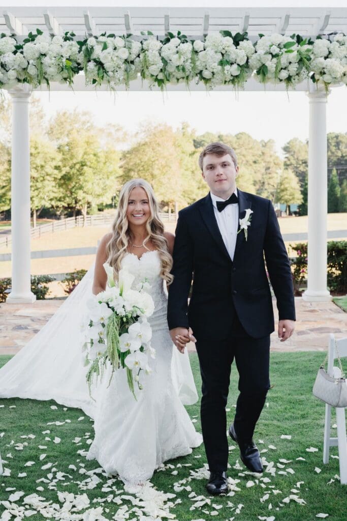 Bride and groom walking down the aisle following their Greenfield Farm wedding ceremony beneath a floral pergola