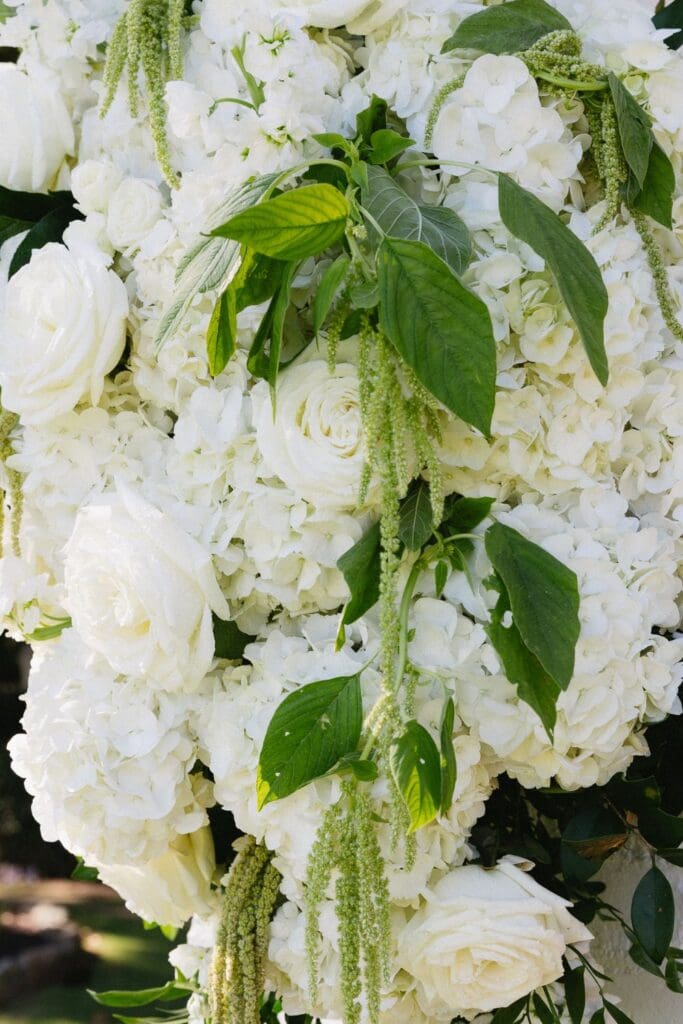 Close-up of lush white hydrangeas, roses, and cascading greenery decorating the Greenfield Farm ceremony pergola.