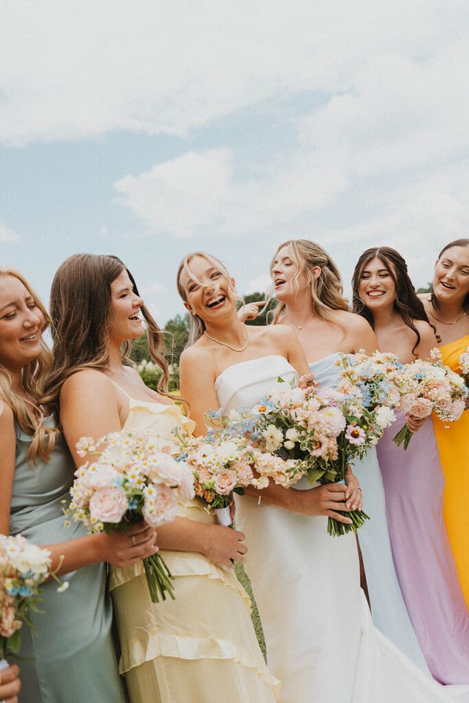 Bride and bridesmaids holding pastel garden style wedding bouquets with roses and seasonal blooms at Meadows at Mossy Creek