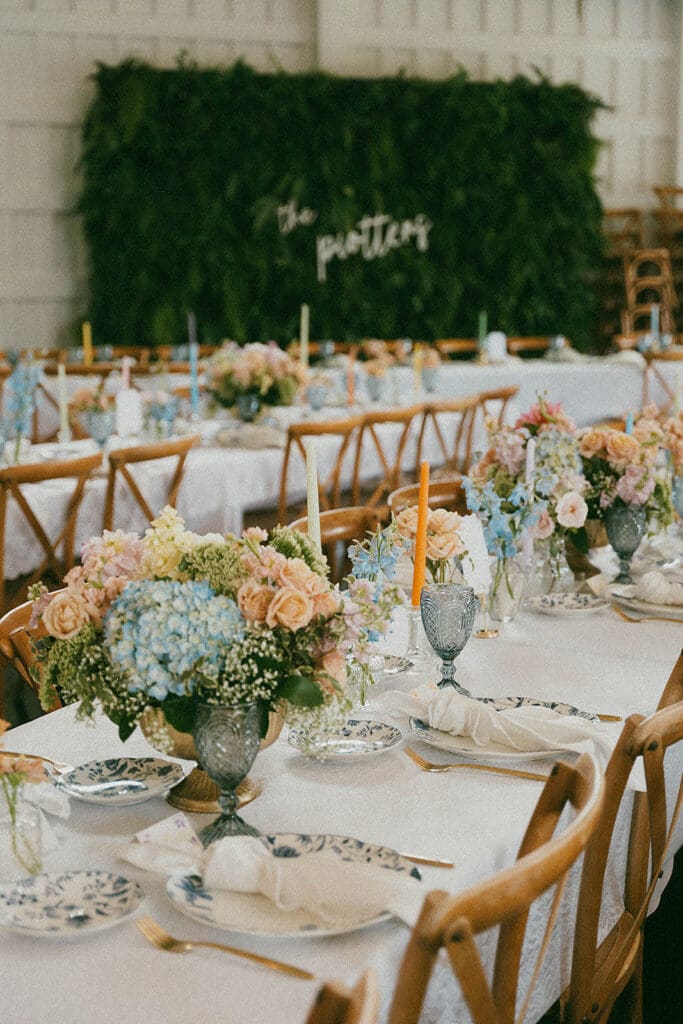 Reception tables with pastel garden style wedding centerpieces and taper candles at Meadows at Mossy Creek wedding venue