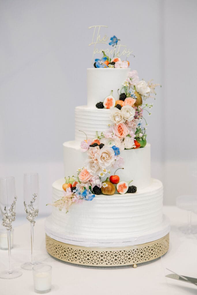Elegant white wedding cake with cascading pastel flowers and fresh fruit designed for a summer wedding at The Revere.