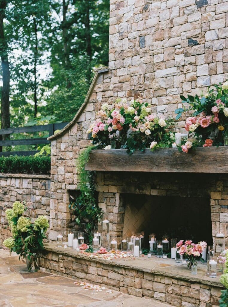 Outdoor stone fireplace decorated with romantic wedding flowers and candles at Greenfield Farms