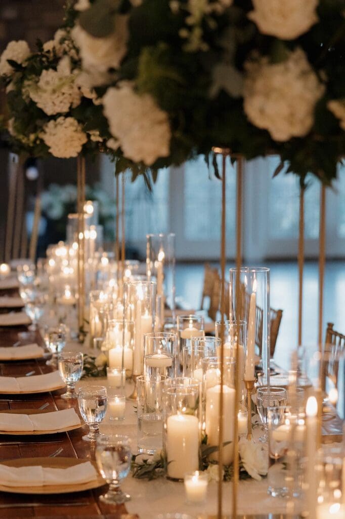 Close up of head table with pillar candles and tall centerpieces at Little Farms