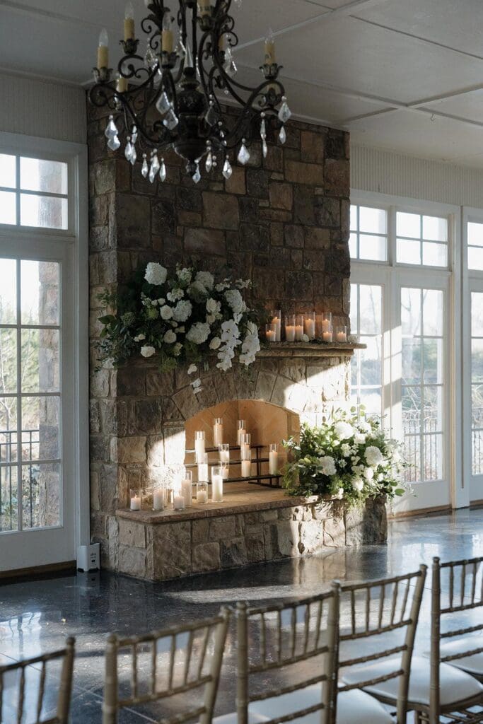 Stone fireplace ceremony backdrop with white hydrangea and rose floral arrangements at Little River Farms wedding