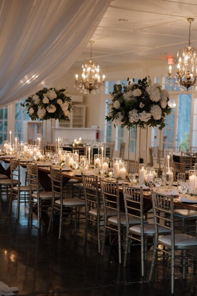 Reception tables with tall white floral centerpieces and candles at Little River Farms