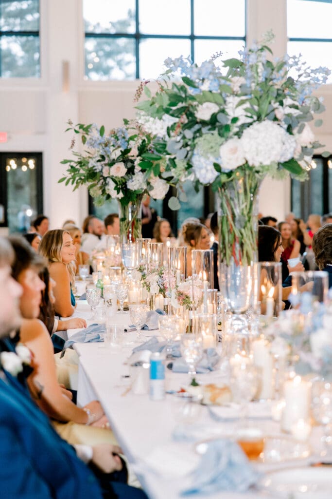 Elegant tall wedding centerpieces with hydrangea, roses, and greenery at a candlelit reception at The Revere wedding venue.