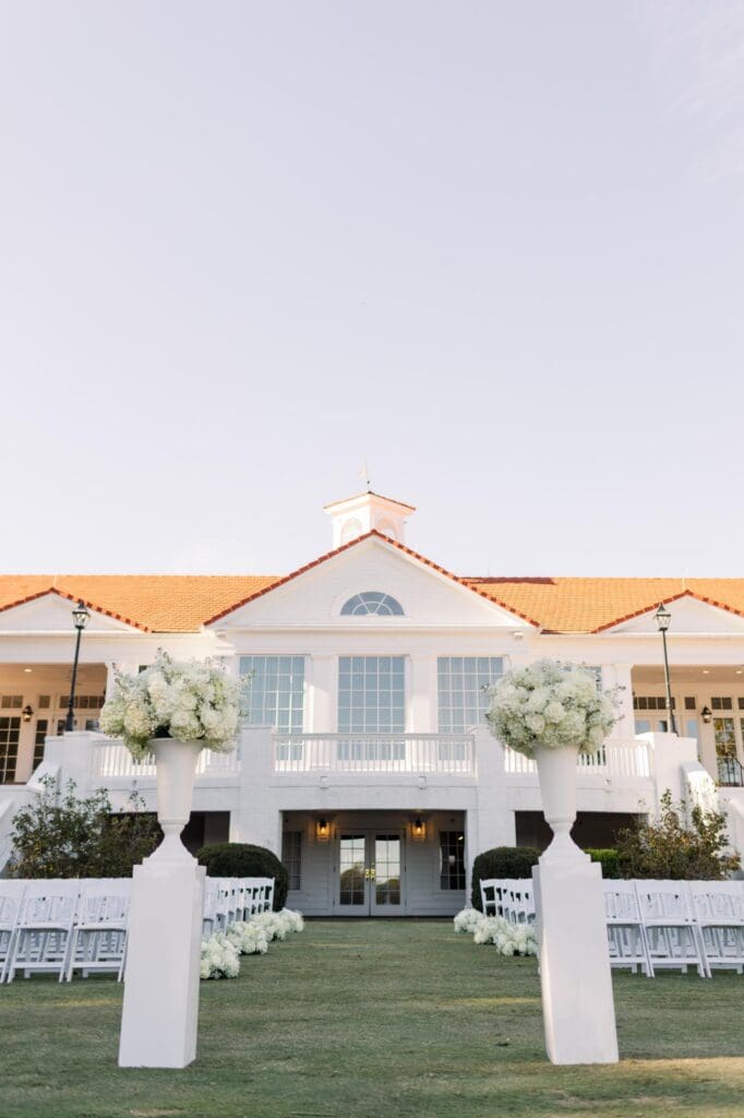 TPC Sugarloaf ceremony site with white chairs, floral aisle arrangements, and large urn flowers