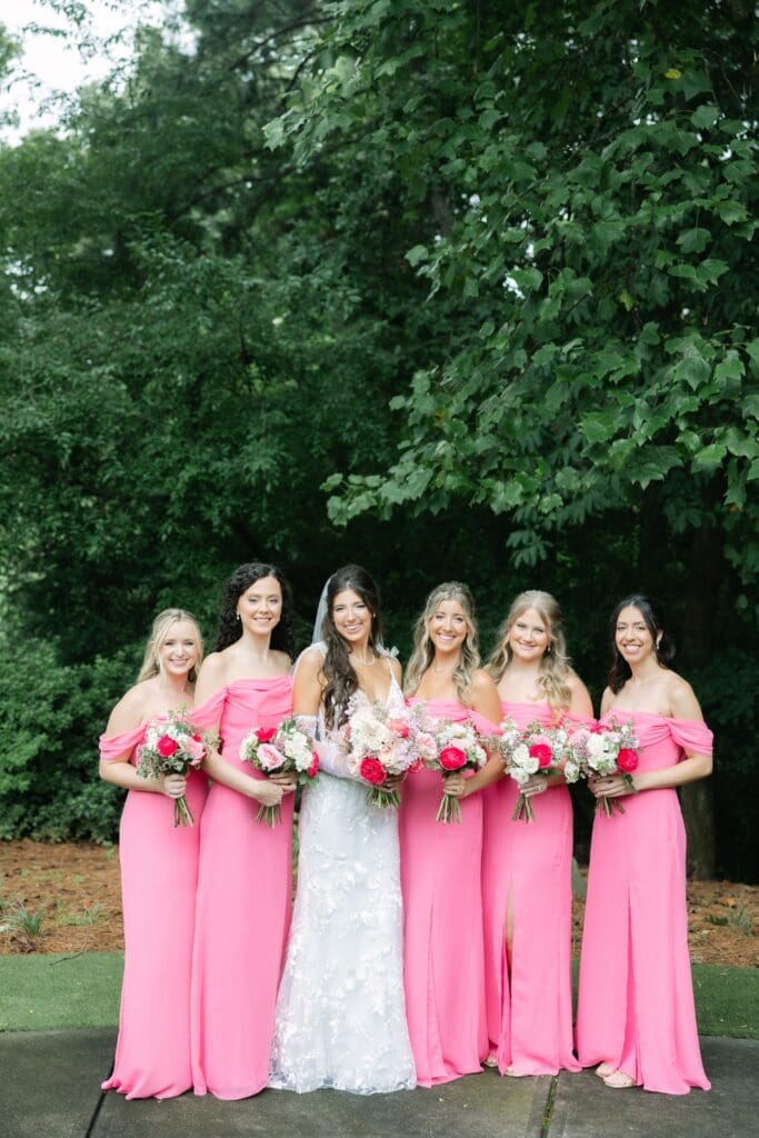 Bride and bridesmaids in pink dresses holding pink and white garden-style bouquets at Country Club of the South wedding.
