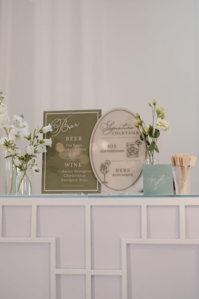 Elegant wedding bar styling with white floral accents and sage green details