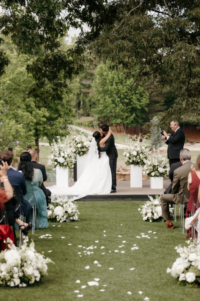 Newlyweds standing between lush white floral ceremony installations at The Revere