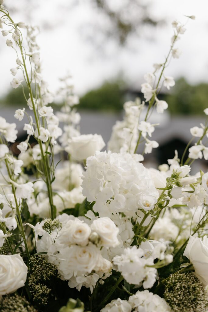 Garden-inspired white hydrangea, roses and delicate line flowers in ceremony arrangement